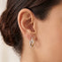 Close-up of woman wearing Engelsrufer infinity paradise tricolour hoop earrings.