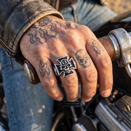 Close-up of a biker's hand on a motorcycle throttle wearing an Iron Cross skull lucky 13 stainless steel ring.
