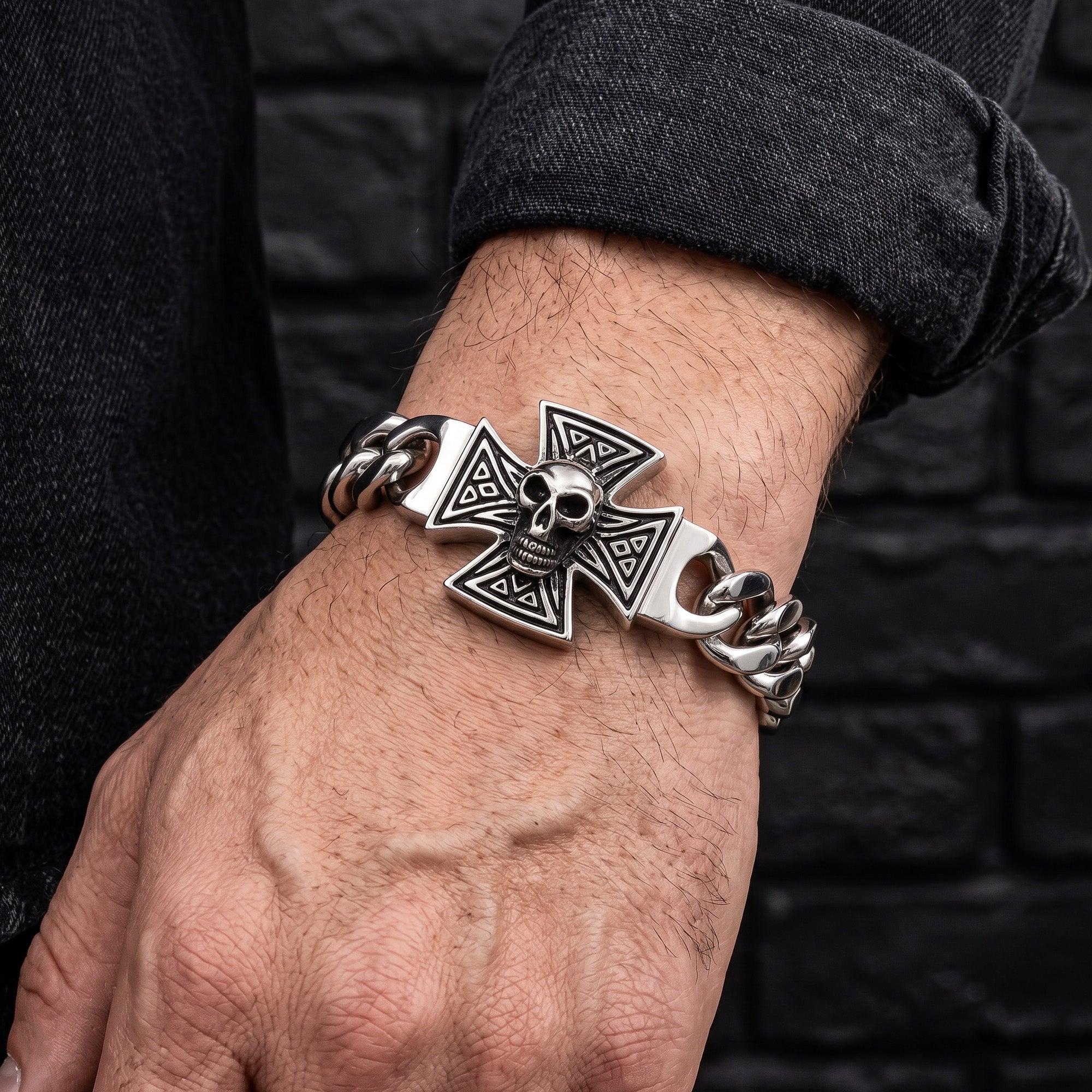 Close-up of a man's wrist wearing an Iron Cross skull Cuban link stainless steel bracelet.