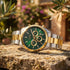 JAG Acton men's green dial two-tone watch sitting on a rock ledge in a courtyard garden
