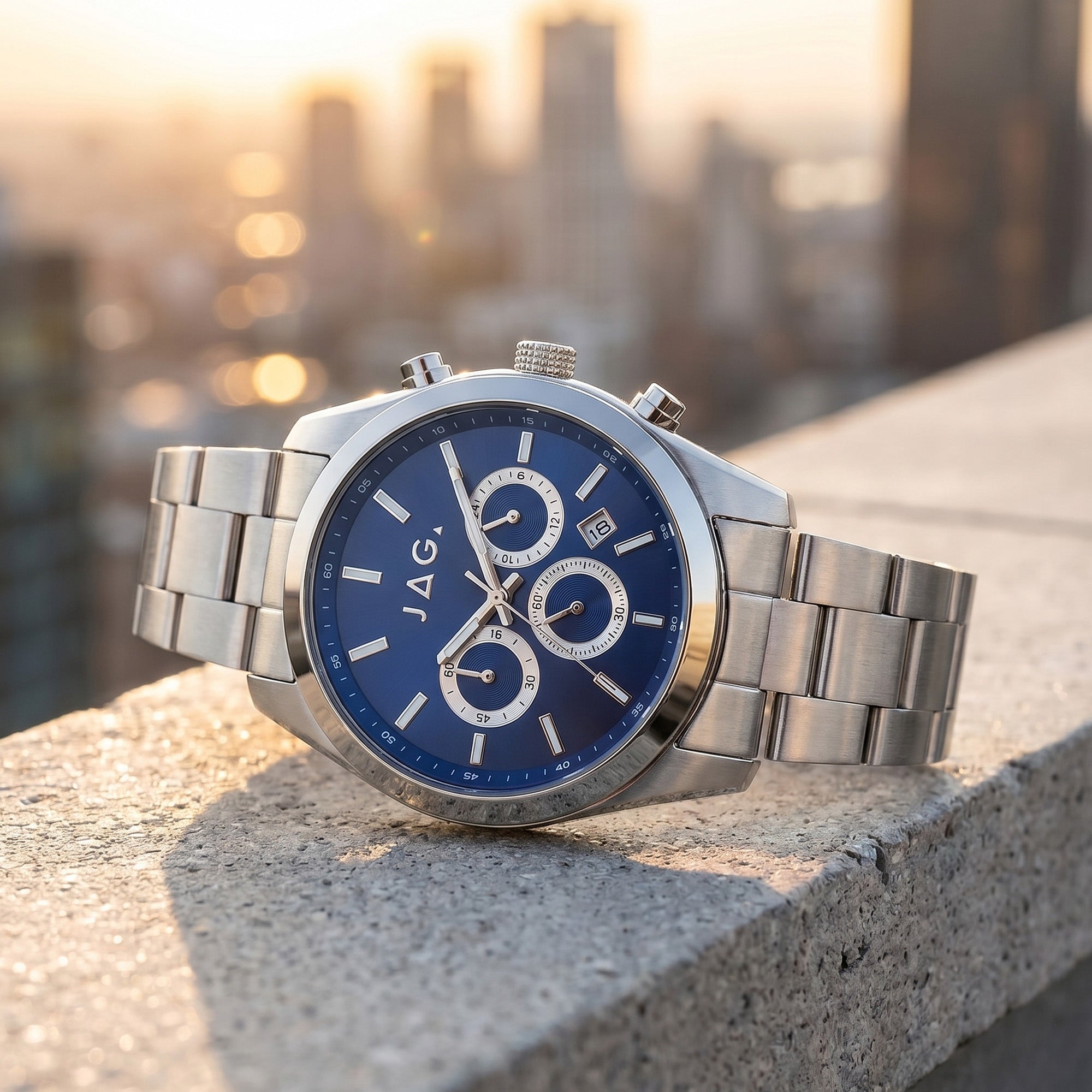 JAG Acton men's blue dial silver watch on a concrete ledge with a skyline of buildings in the background.