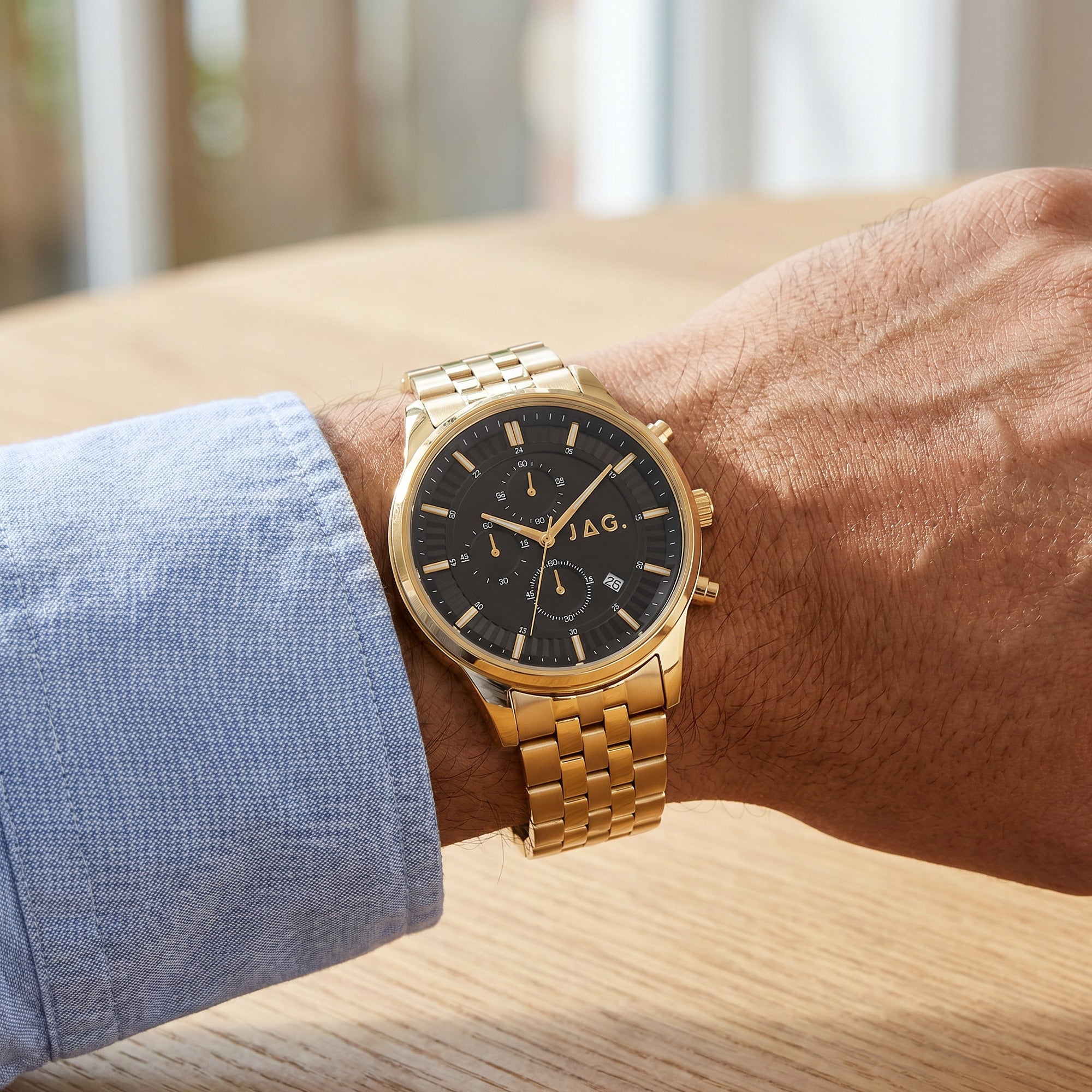 Man wearing JAG Albany men's black dial gold watch on his wrist.