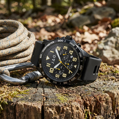 JAG Beachport black sport chronograph men's watch sitting on a tree log with climbing rope on an outdoor trail.