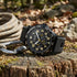 JAG Beachport black sport chronograph men's watch sitting on a tree log with climbing rope on an outdoor trail.