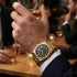 Man wearing a JAG Beaufort black dial gold men's watch at a drinks gathering.