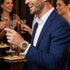 Man wearing a JAG Beaufort black dial gold men's watch surrounded by people at a social event.