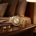 JAG Gerroa gold transparent men's watch laying on a wooden side table with gold cufflinks.