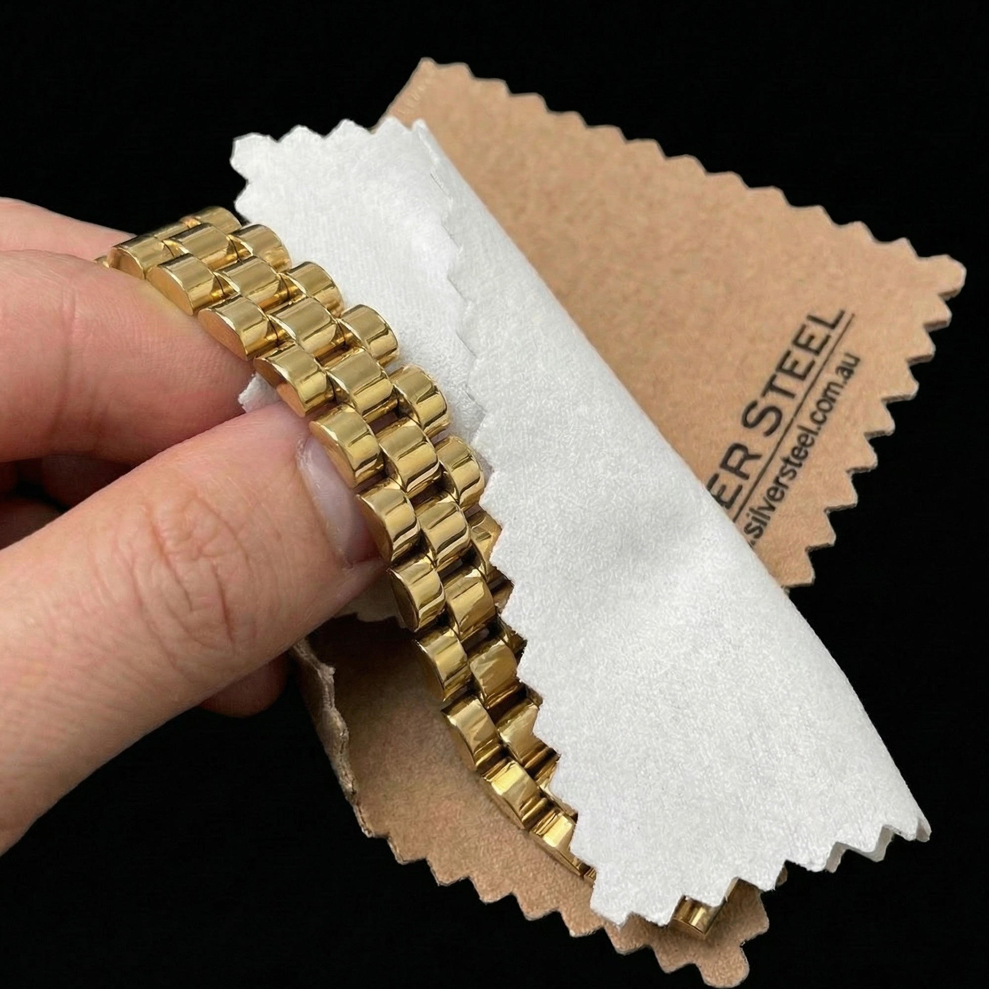 Gold bracelet being polished with a jewellery cleaning and polishing cloth.