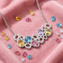 Kagi prismatic gemstone reversible statement necklace on pink velvet surrounding by coloured gemstones.