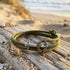 Anchor & Crew Admiral silver khaki green rope bracelet on a wooden step near the beach.