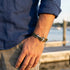Man wearing Anchor & Crew Admiral silver khaki green rope bracelet on wrist.