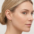 Woman wearing Engelsrufer little angel gold hoop earrings.