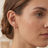 Woman wearing Engelsrufer little angel rose gold hoop earrings.