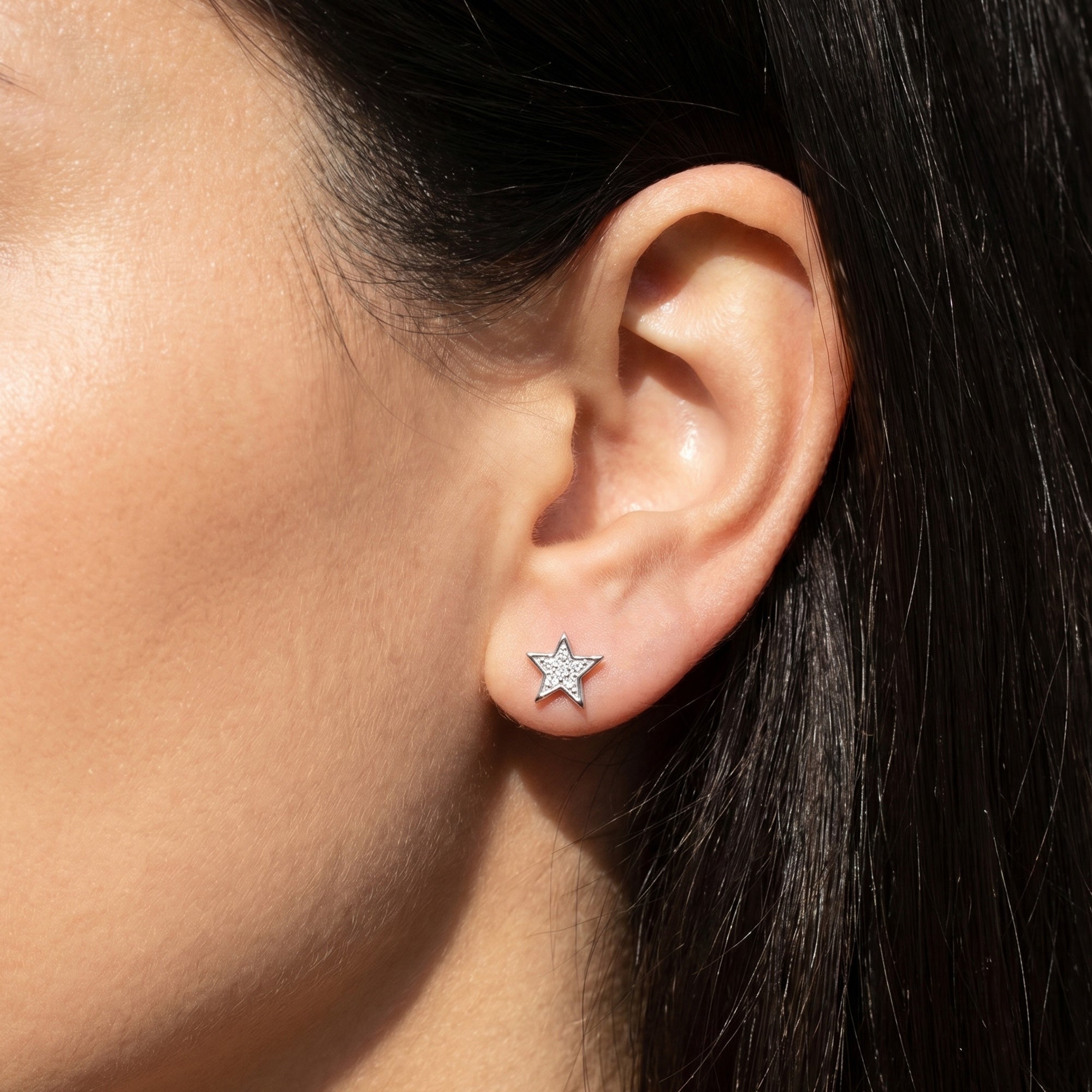 Woman wearing Engelsrufer little star sterling silver CZ earrings.