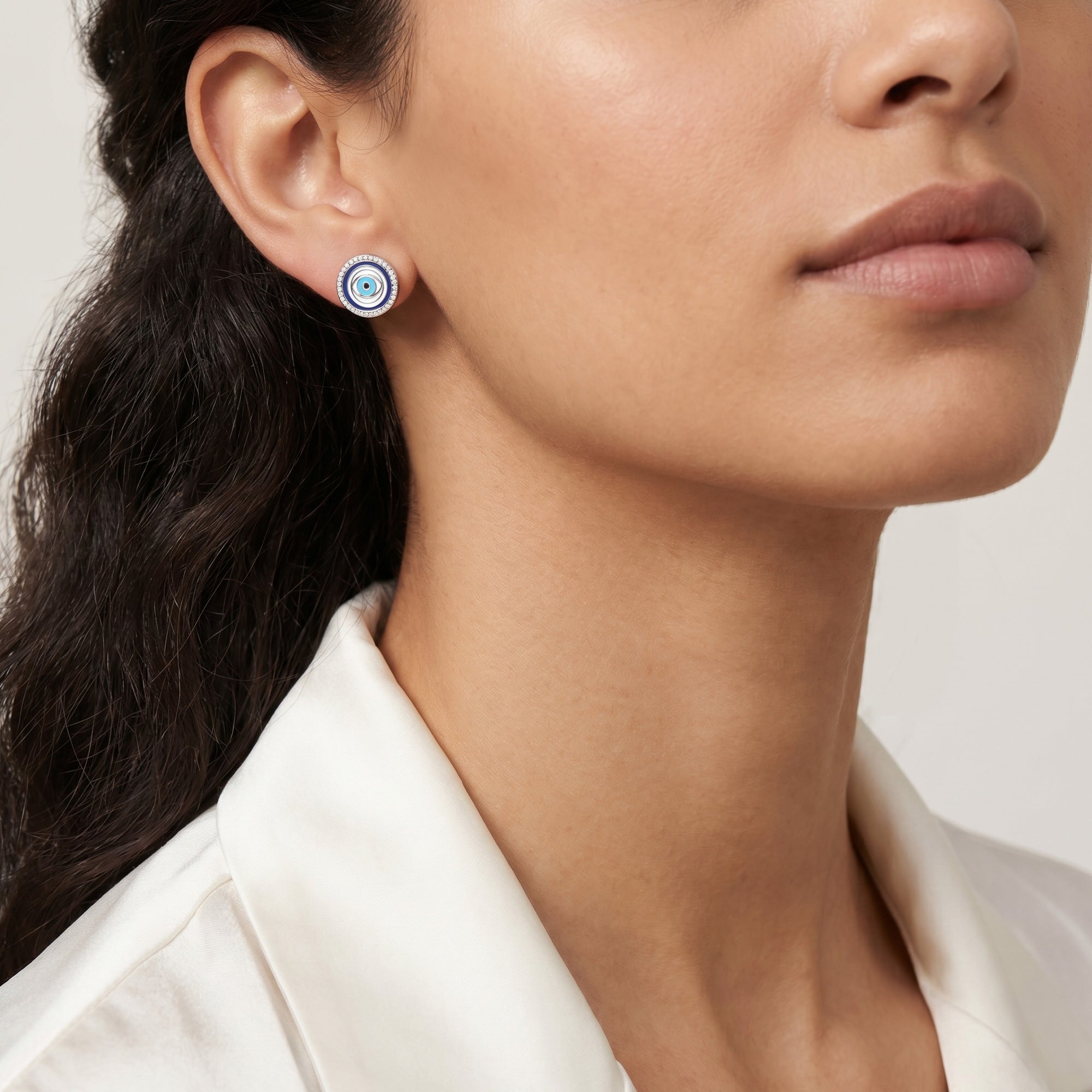 Close-up of woman wearing Engelsrufer lucky eye silver blue enamel circle earrings.