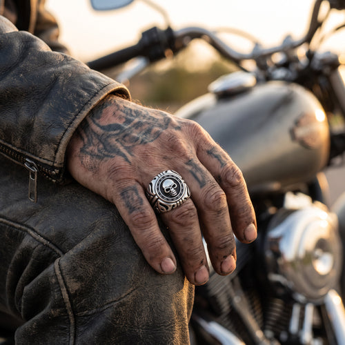Man sitting on a motorcycle wearing a memento mori skull stainless steel signet ring.