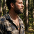 Side view of man in an open-neck shirt standing in the bush wearing military star dog tag necklace.