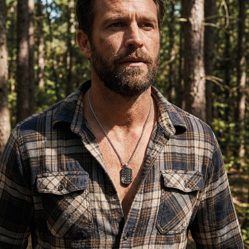 Man in an open-neck shirt standing in the bush wearing military star dog tag necklace.