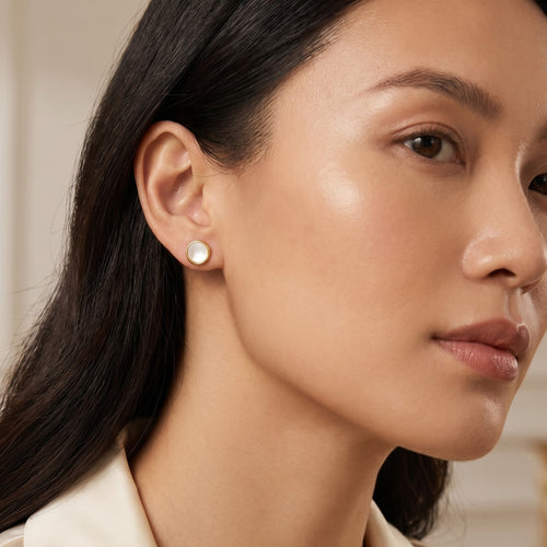 Woman wearing Engelsrufer mother of pearl gold disc earrings.