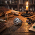 A pentagram stainless steel men's signet ring on an old wooden table with leather books and scrolls in an apothecary.