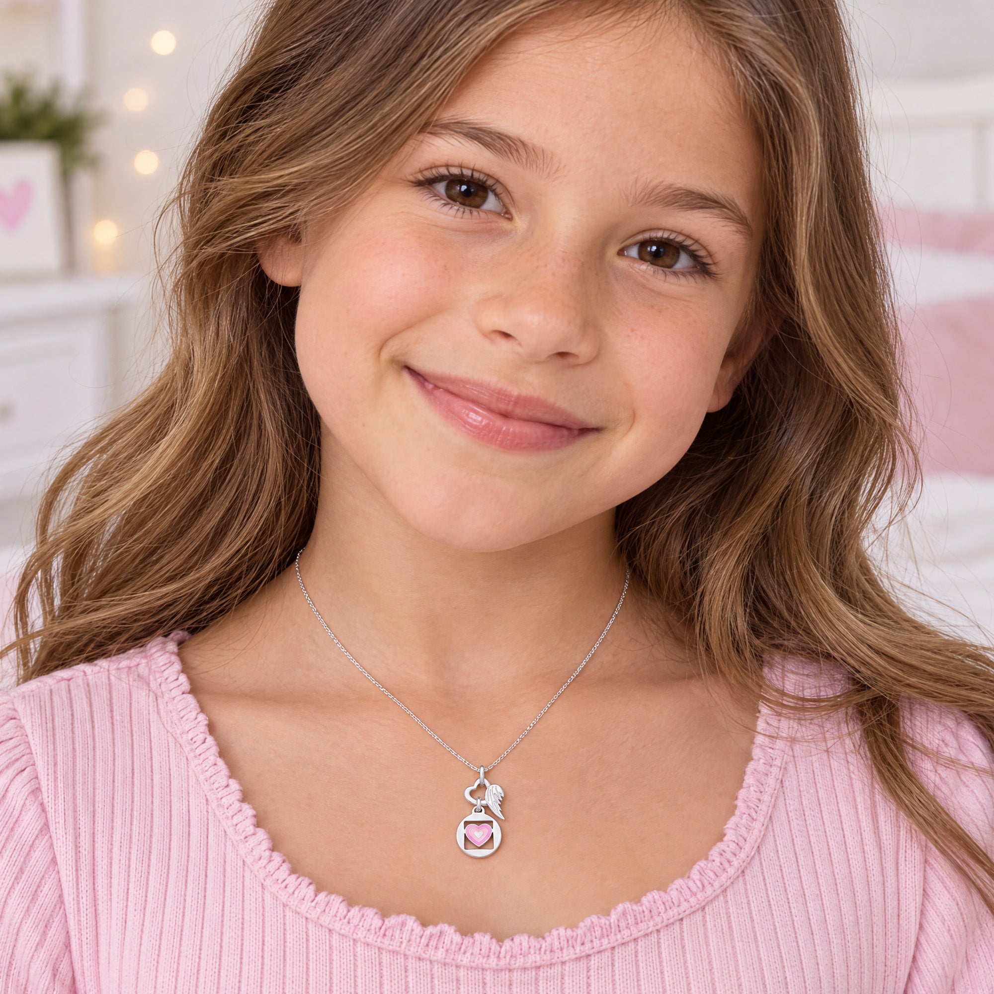 Young girl wearing Herzengel pink love heart wing silver children's necklace.