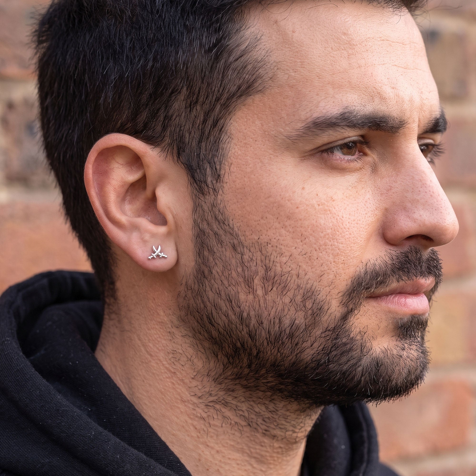 Side profile of man wearing pirate swords stainless steel stud earring.