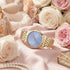 Police ladies Celebration powder blue dial gold watch on pink fabric surrounded by roses.