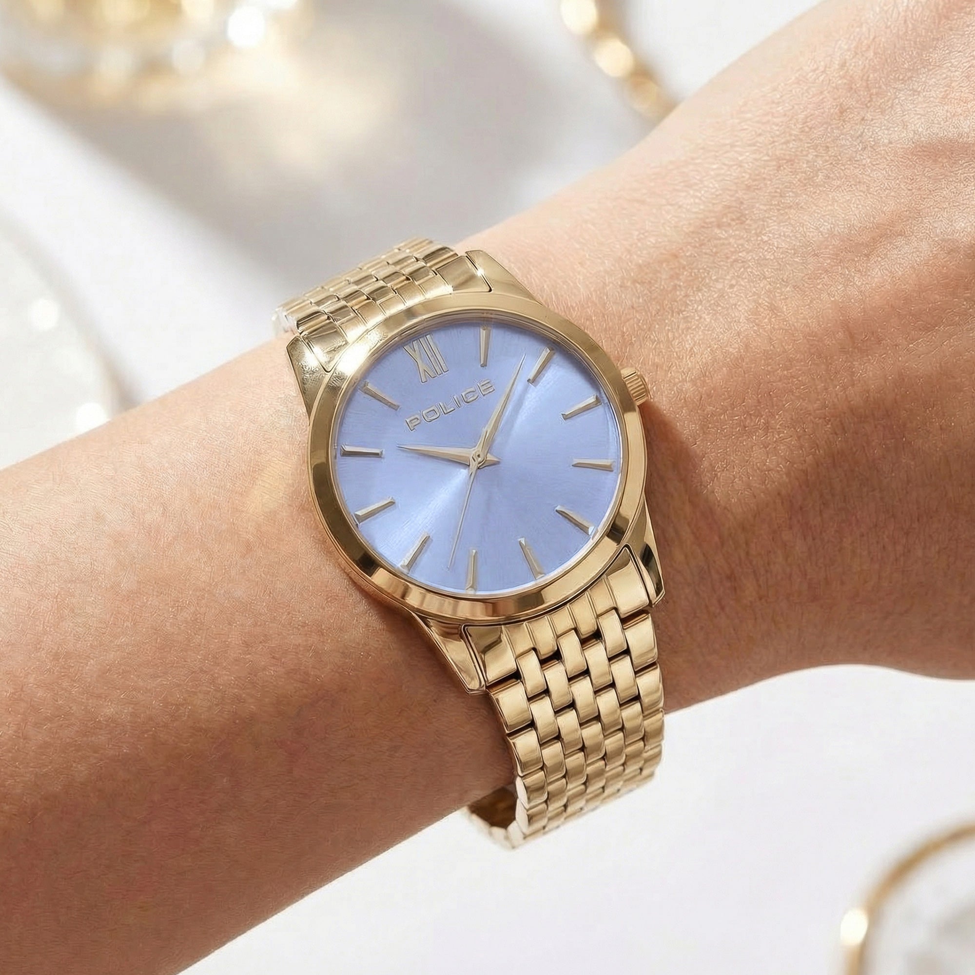 Woman wearing Police ladies Celebration powder blue dial gold watch.