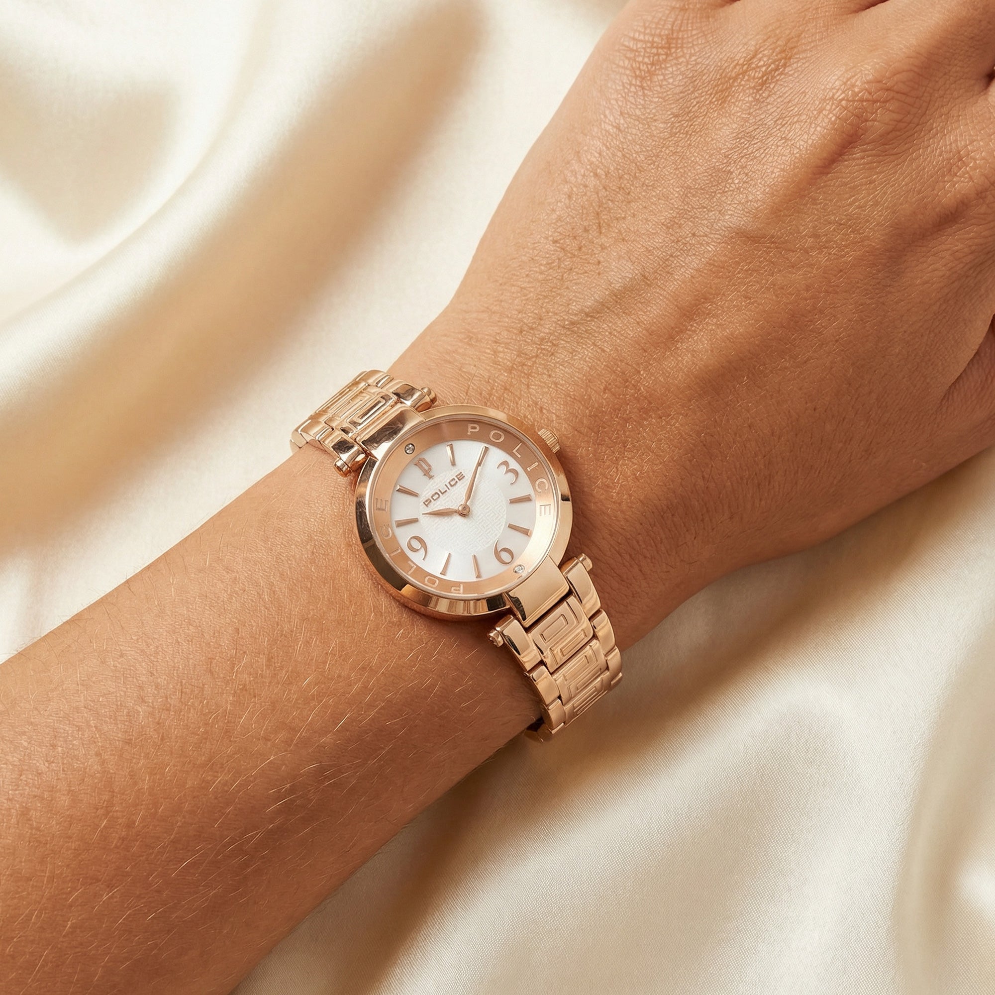 Close-up of a woman wearing Police ladies Attraction pearl dial rose gold watch on her wrist.