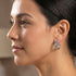 Side view of woman looking to the left wearing Ellani rainbow silver channel set hoop earrings.
