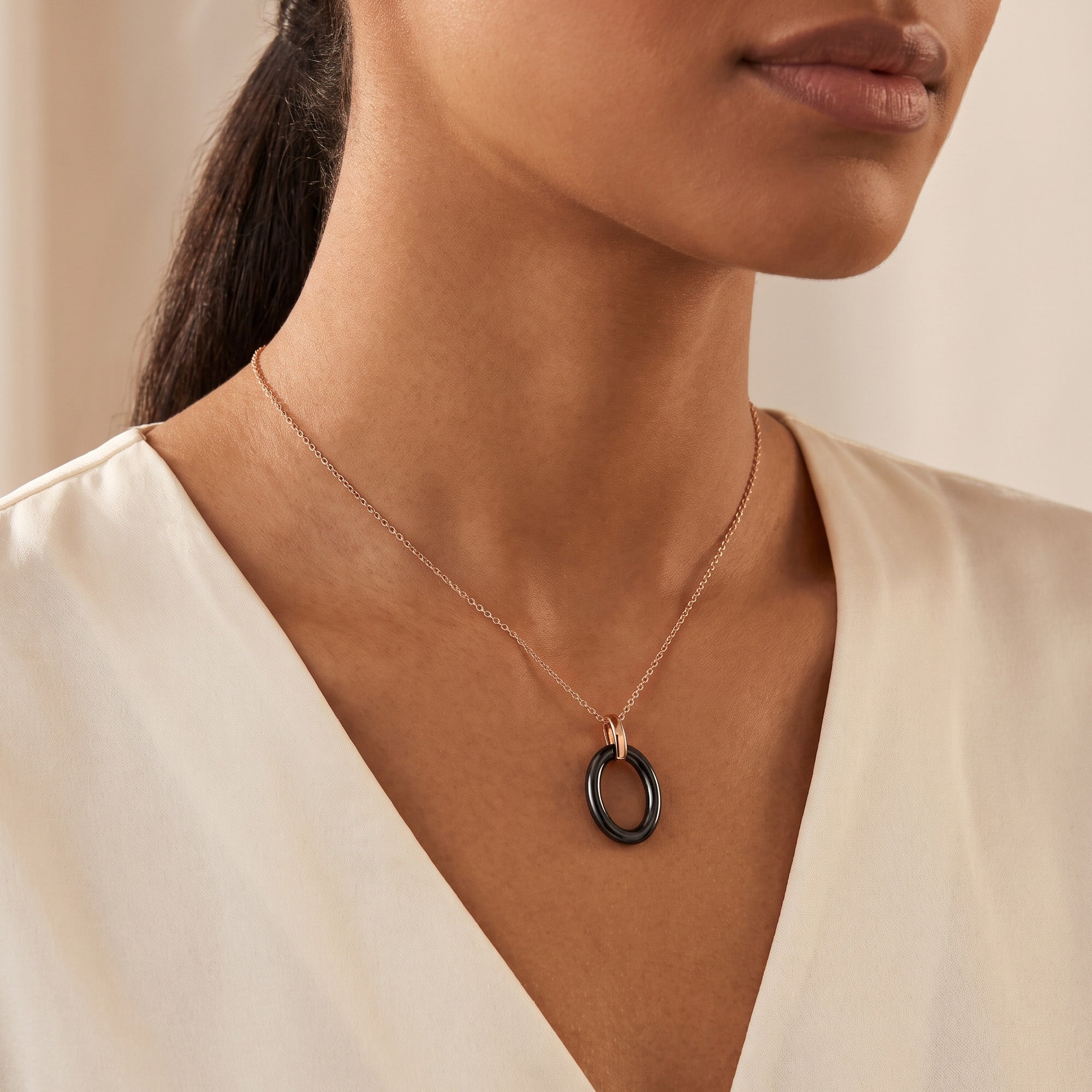 Woman wearing a sterling silver rose gold black ceramic oval necklace.