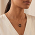 Woman wearing a sterling silver rose gold black ceramic oval necklace.