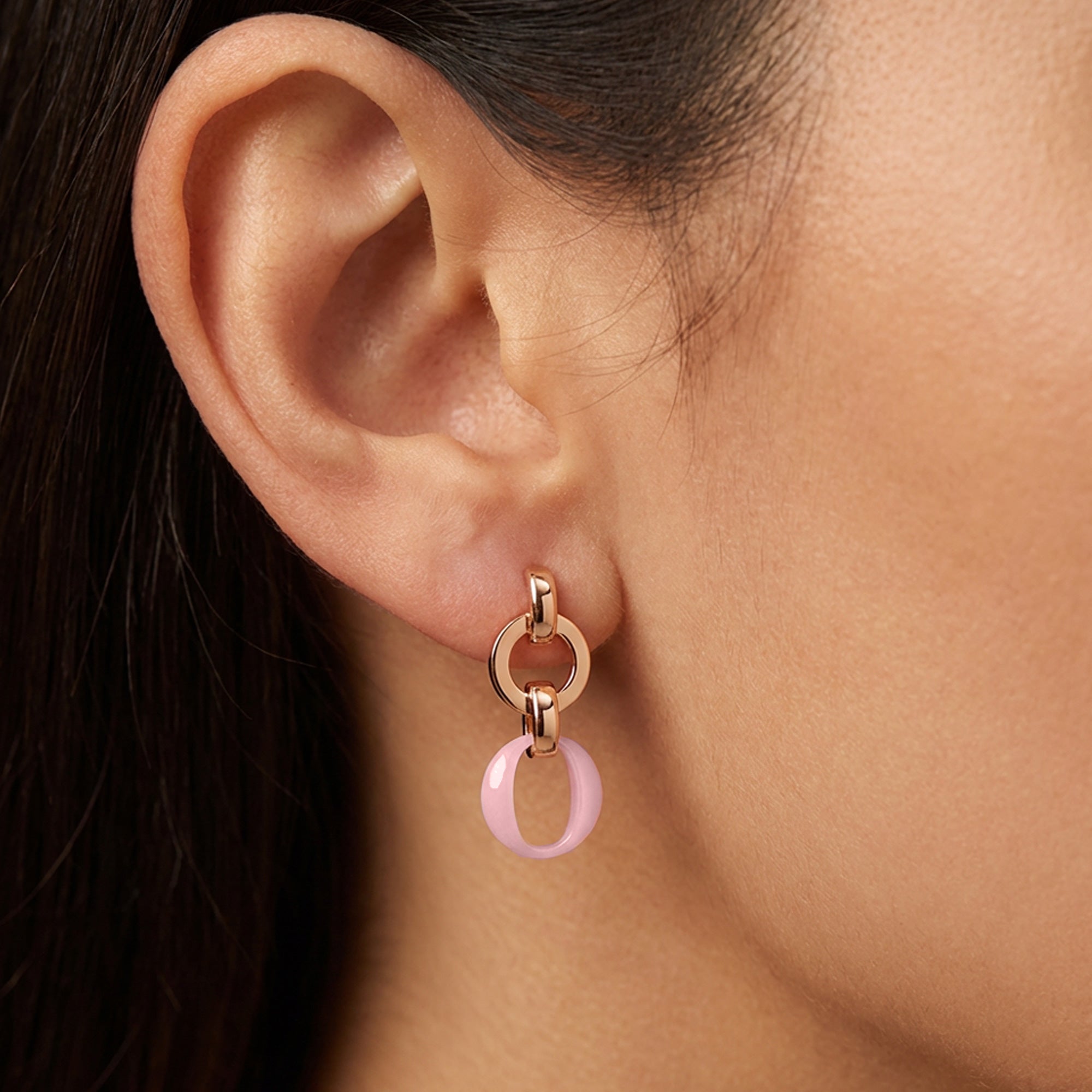 Close up of a woman wearing sterling silver rose gold pink ceramic circle link earrings.