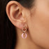 Close up of a woman wearing sterling silver rose gold pink ceramic circle link earrings.