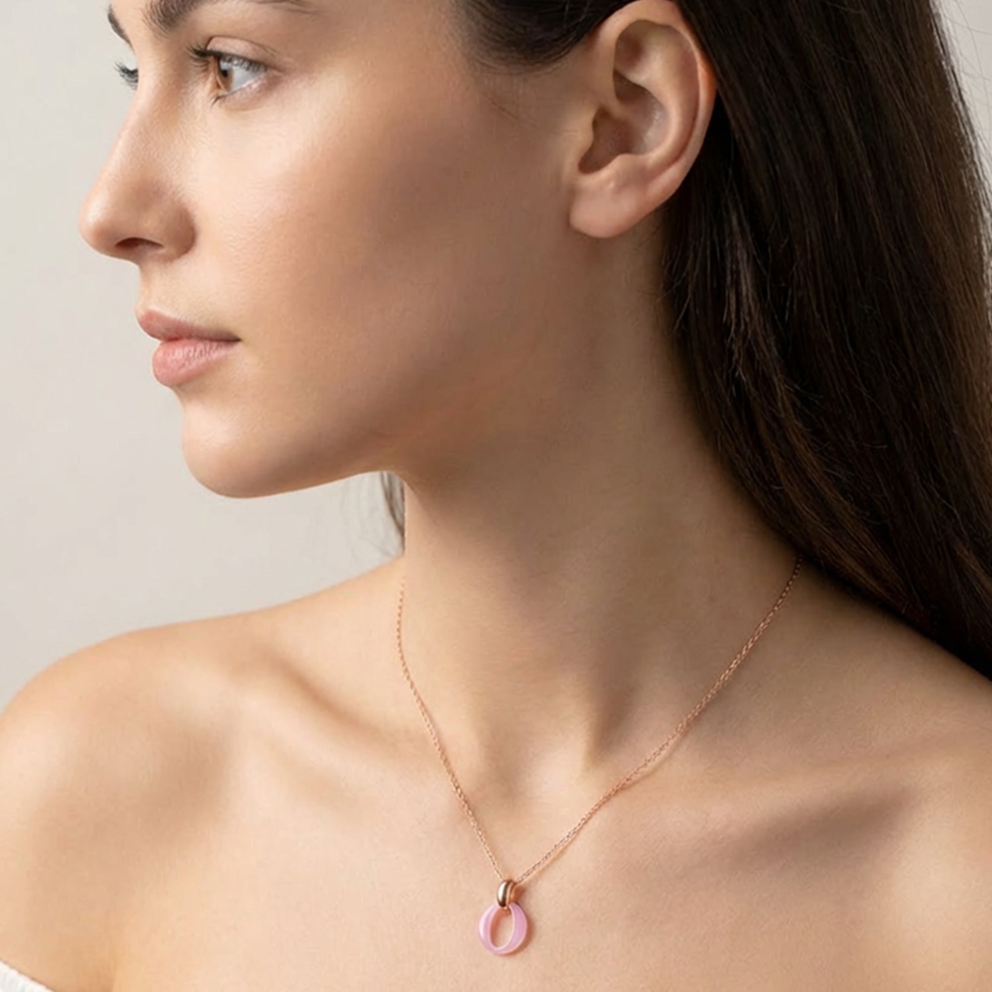 Woman wearing a sterling silver rose gold pink ceramic circle necklace.