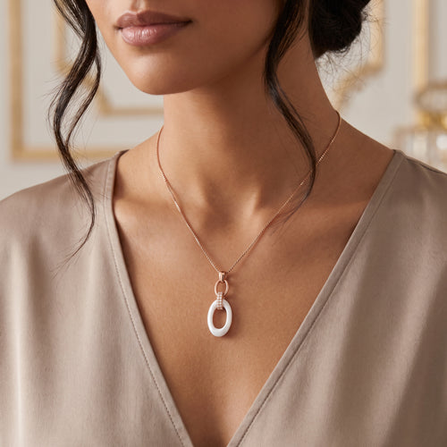 Woman wearing a sterling silver rose gold white ceramic oval link CZ necklace.