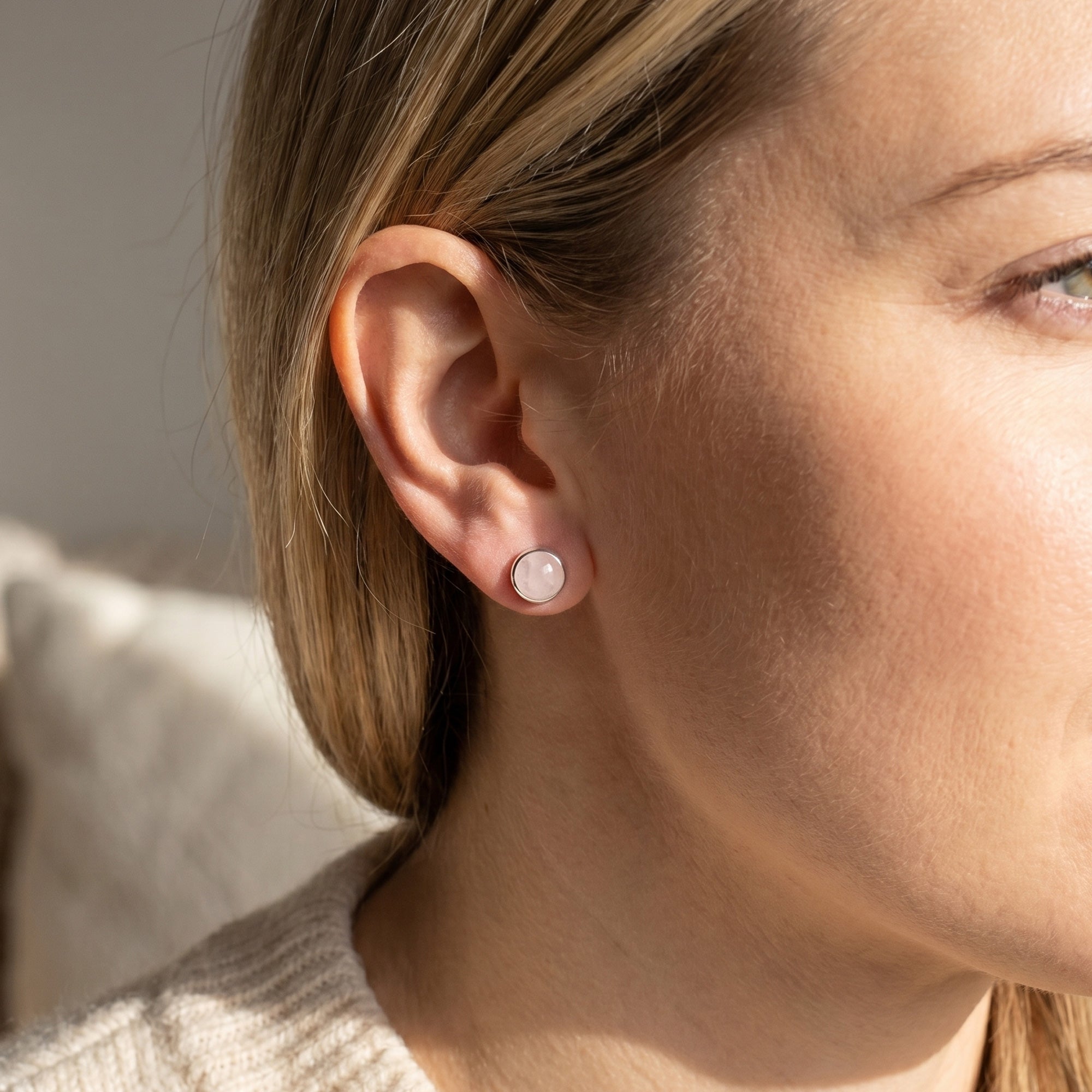 Woman wearing Engelsrufer rose quartz cabochon silver stud earrings.