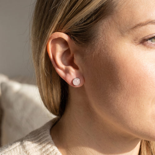 Woman wearing Engelsrufer rose quartz cabochon silver stud earrings.