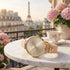 Sara Miller Chelsea Charm 34mm sunray dial gold watch on balcony table in France with the Eiffel Tower in the background.