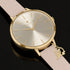 Sara Miller Chelsea Charm 34mm sunray dial gold watch on a mirrored surface.