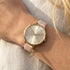 Woman wearing Sara Miller Chelsea Charm 34mm sunray dial gold watch.