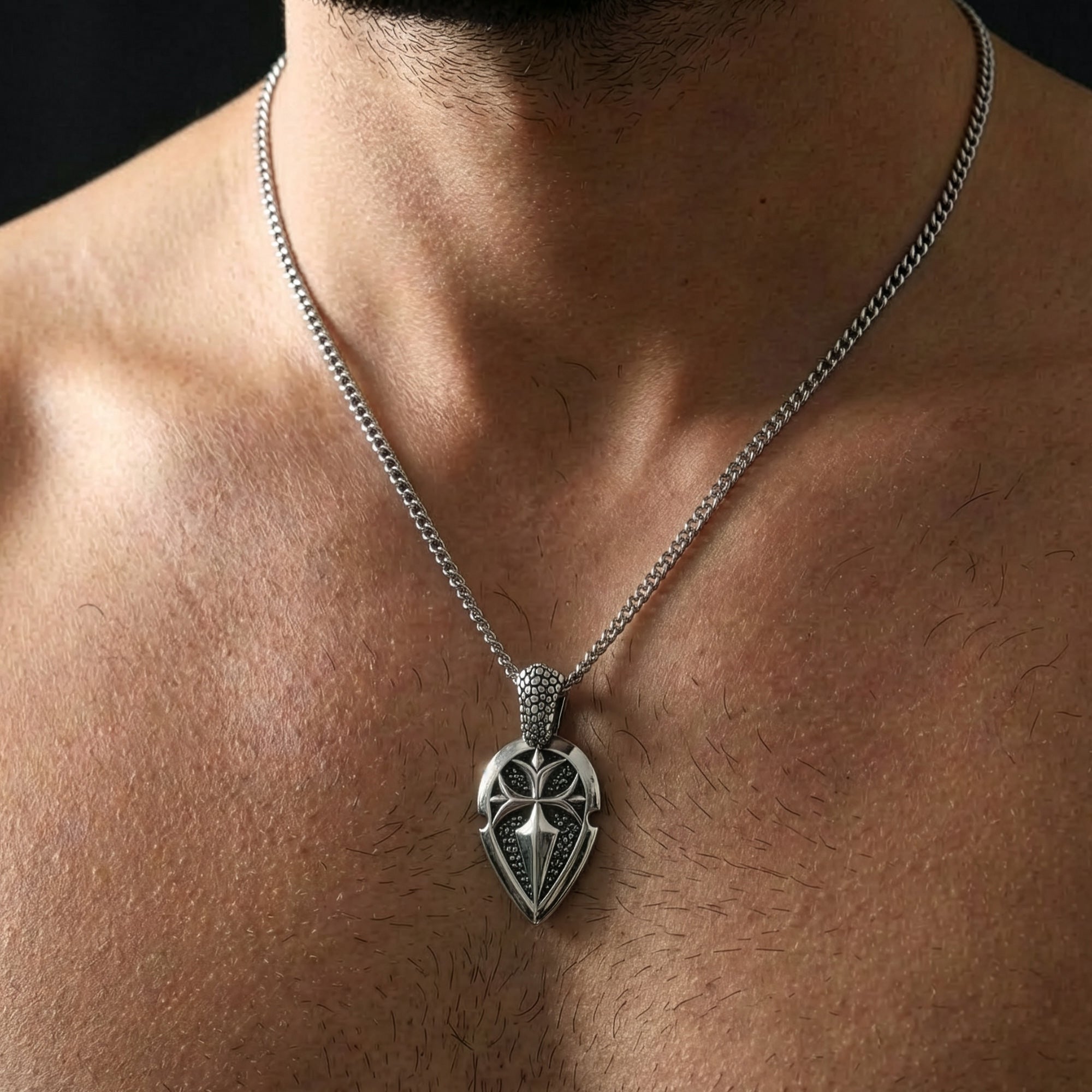 Close-up of a shirtless man wearing a shield cross stainless steel necklace.