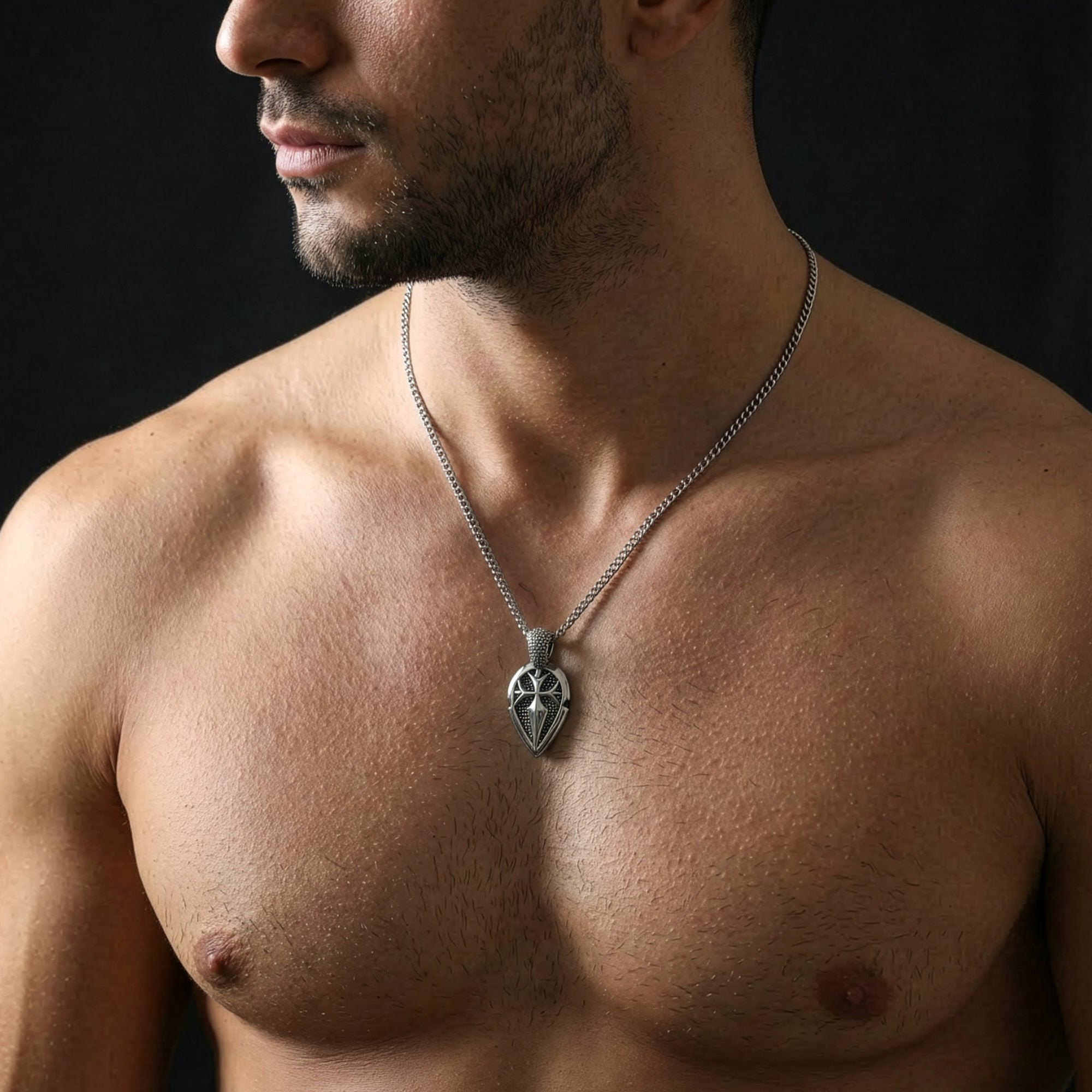Shirtless man looking to the left wearing a shield cross stainless steel necklace.