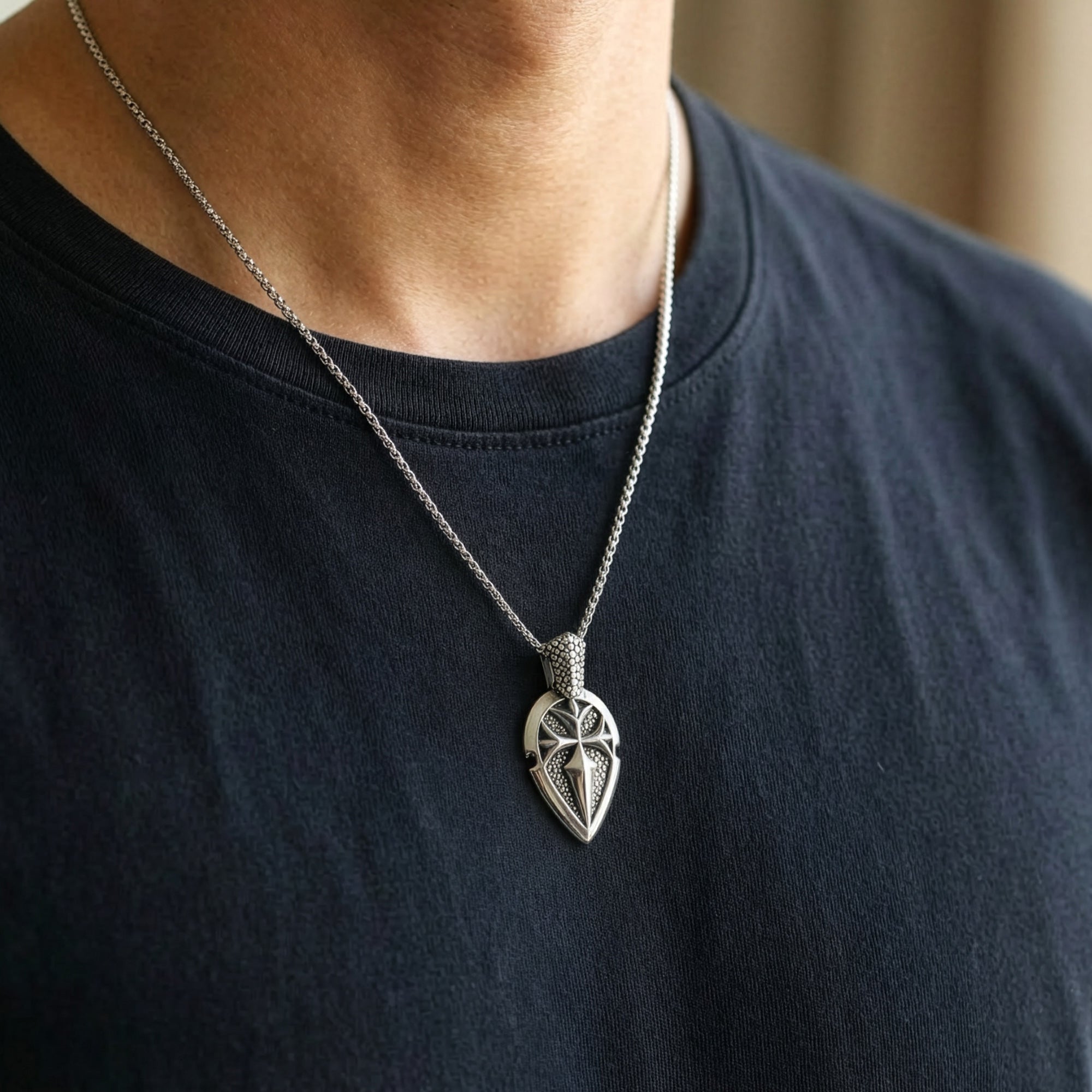 Man in a blue t-shirt wearing a shield cross stainless steel necklace.