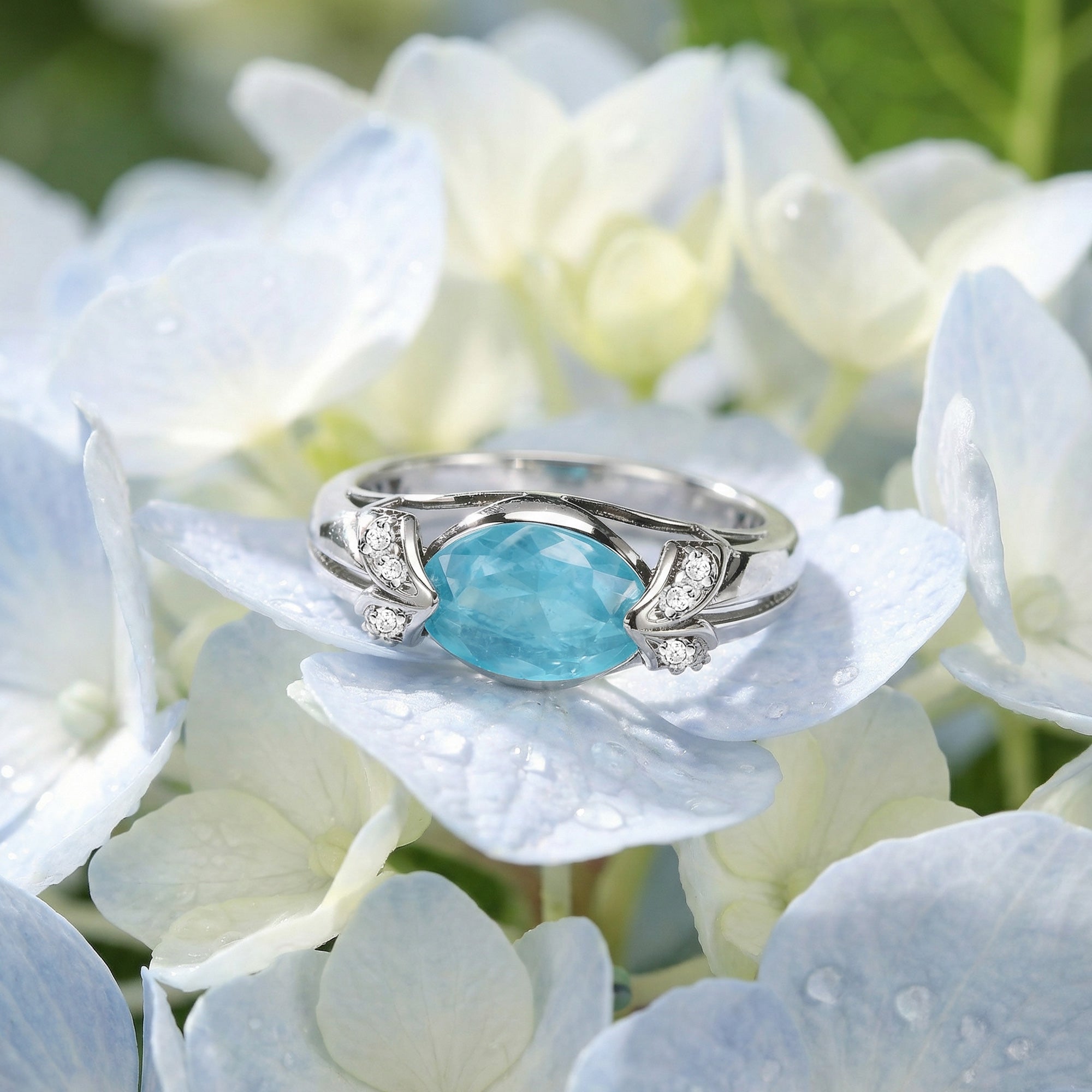 Sterling silver oval cut aquamarine ladies ring resting on white flower petals.
