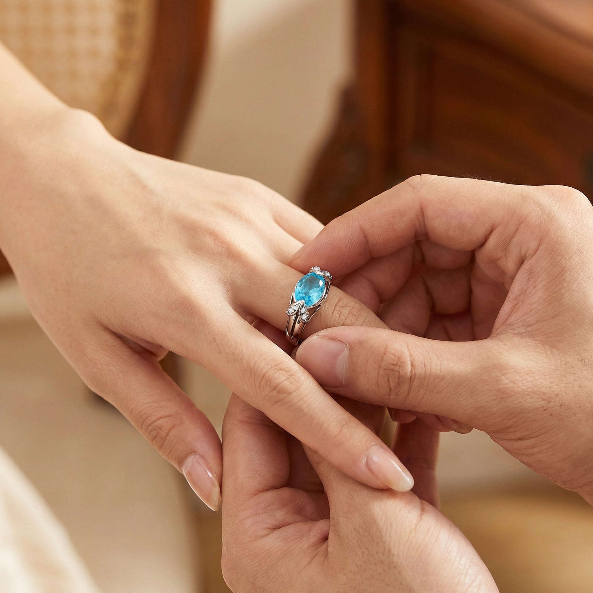 Man placing sterling silver oval cut aquamarine ladies ring on a woman's hand.