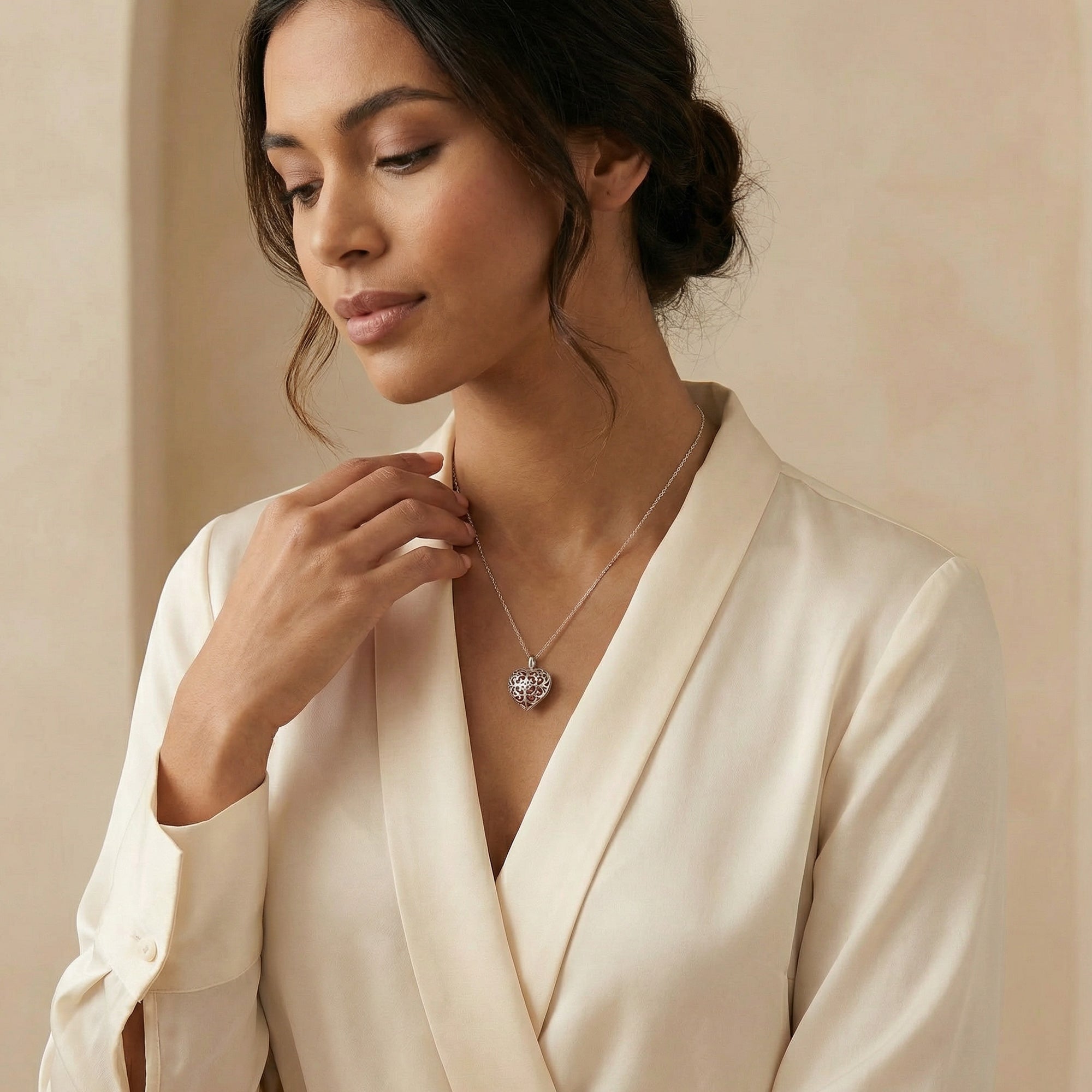 Woman in white blouse wearing an Engelsrufer sterling silver red heart soundball necklace.
