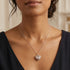 Woman in open-neck blouse wearing an Engelsrufer sterling silver rose gold heart soundball necklace.
