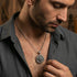 Man in open-neck shirt wearing sterling silver men's silver Tibetan vajra cross amulet necklace.