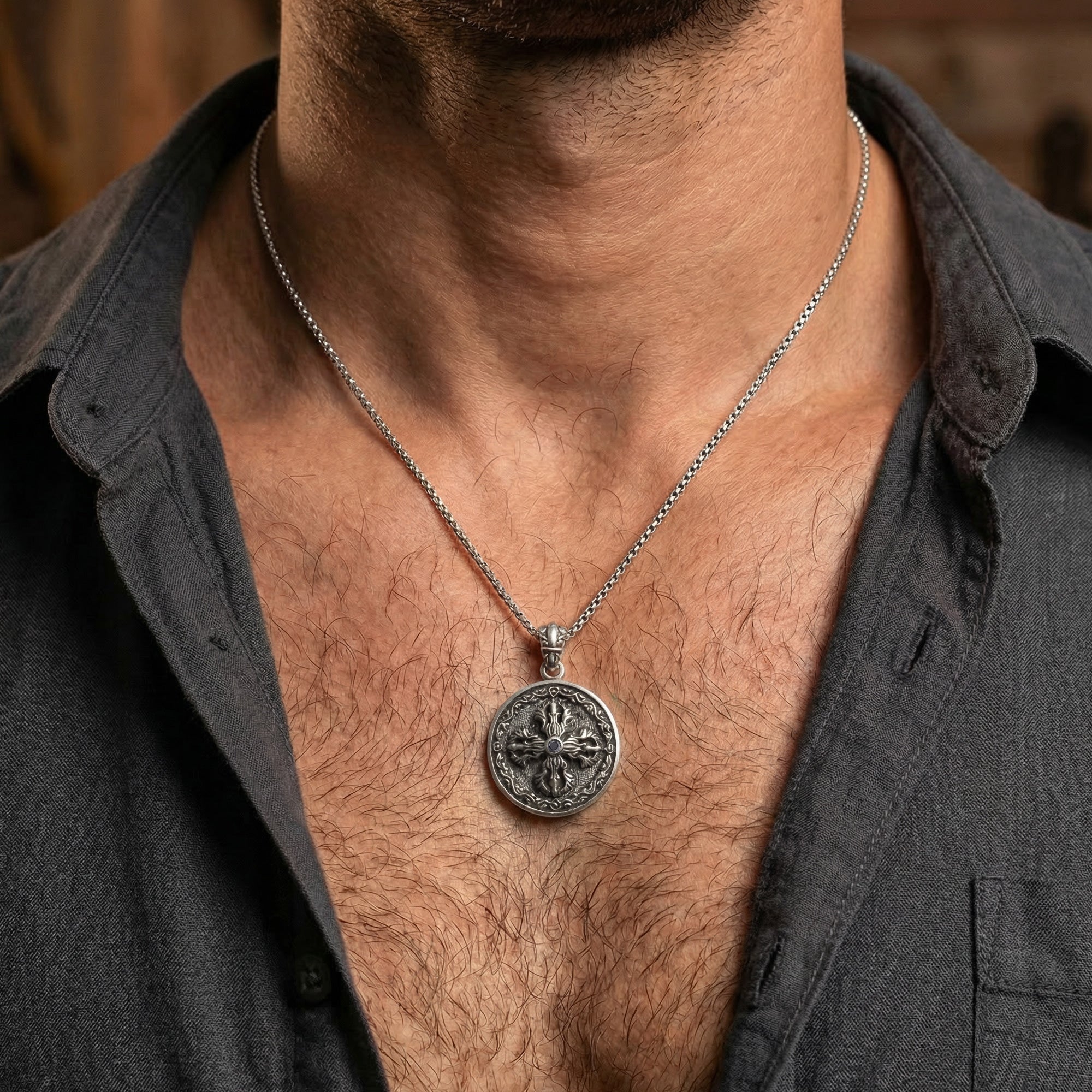 Close-up of man in open-neck shirt wearing sterling silver men's silver Tibetan vajra cross amulet necklace.